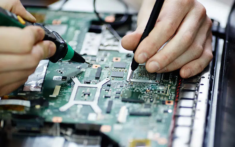 AURA-solder-PCB-AdobeStock_136939755-800×500 Grande plano de mãos humanas usando um ferro de soldar numa placa de circuito impresso.